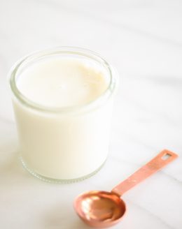 Jar of homemade buttermilk next to copper measuring spoon