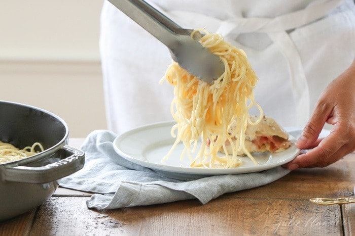 Using tongs to serve the fontina cheese pasta on to a plate