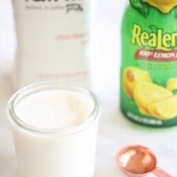 Homemade buttermilk in small glass jar in front of milk carton and bottle of lemon juice