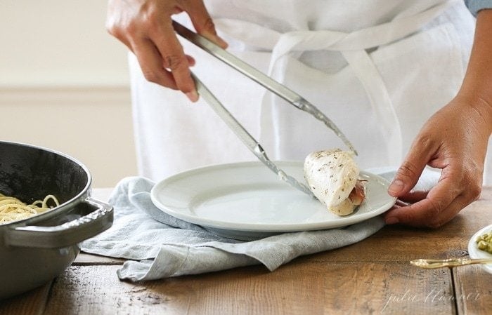 Placing the cheese stuffed chicken breast on a plate with tongs