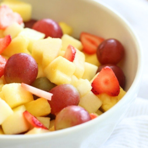 A bowl of easy vanilla fruit salad containing strawberries, grapes, and diced mango.