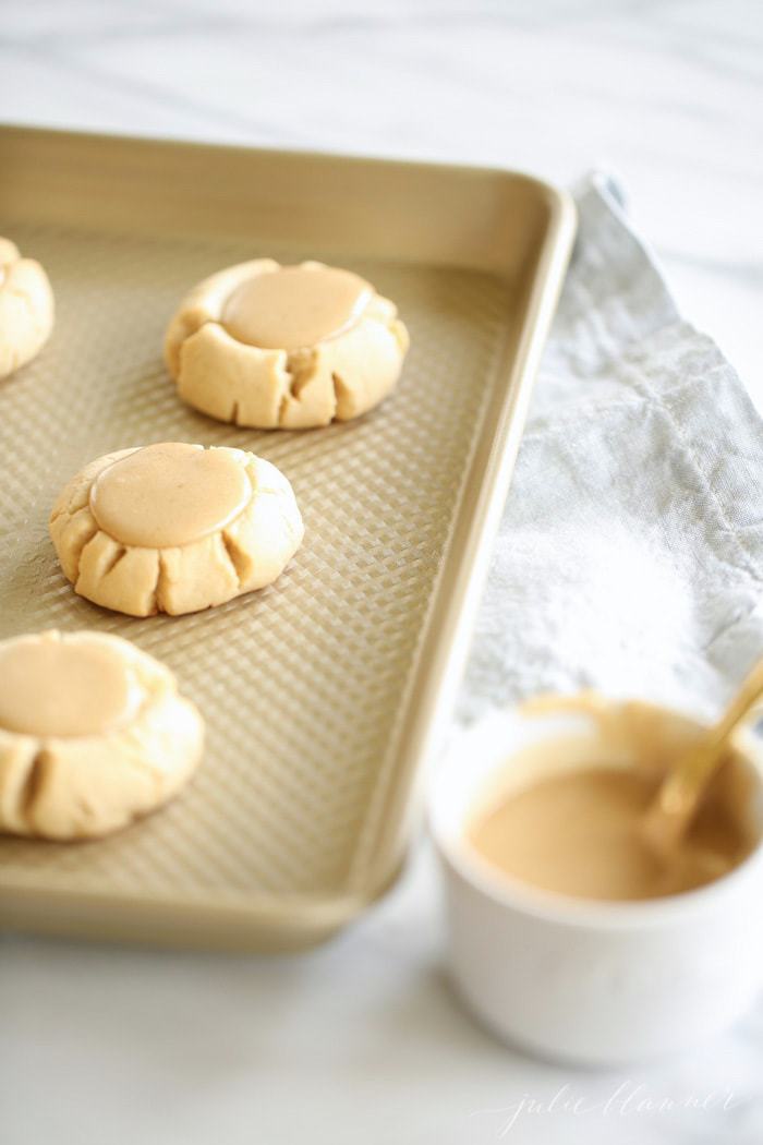 Sugar cookies with salted caramel icing on a baking sheet