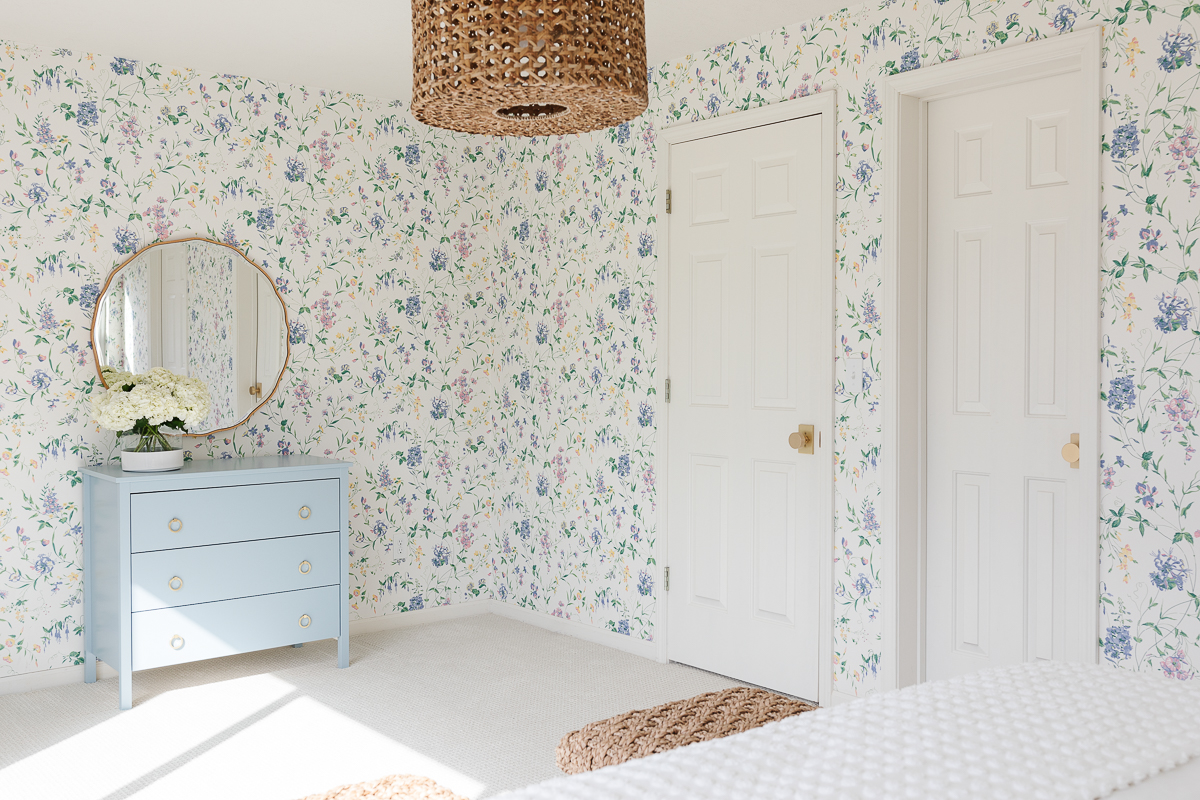 A bedroom with floral dated wallpaper.