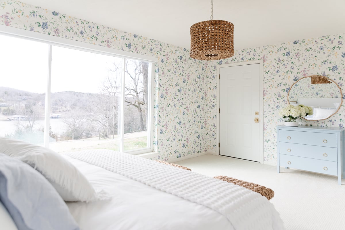 A bedroom with dated floral wallpaper and a dresser.