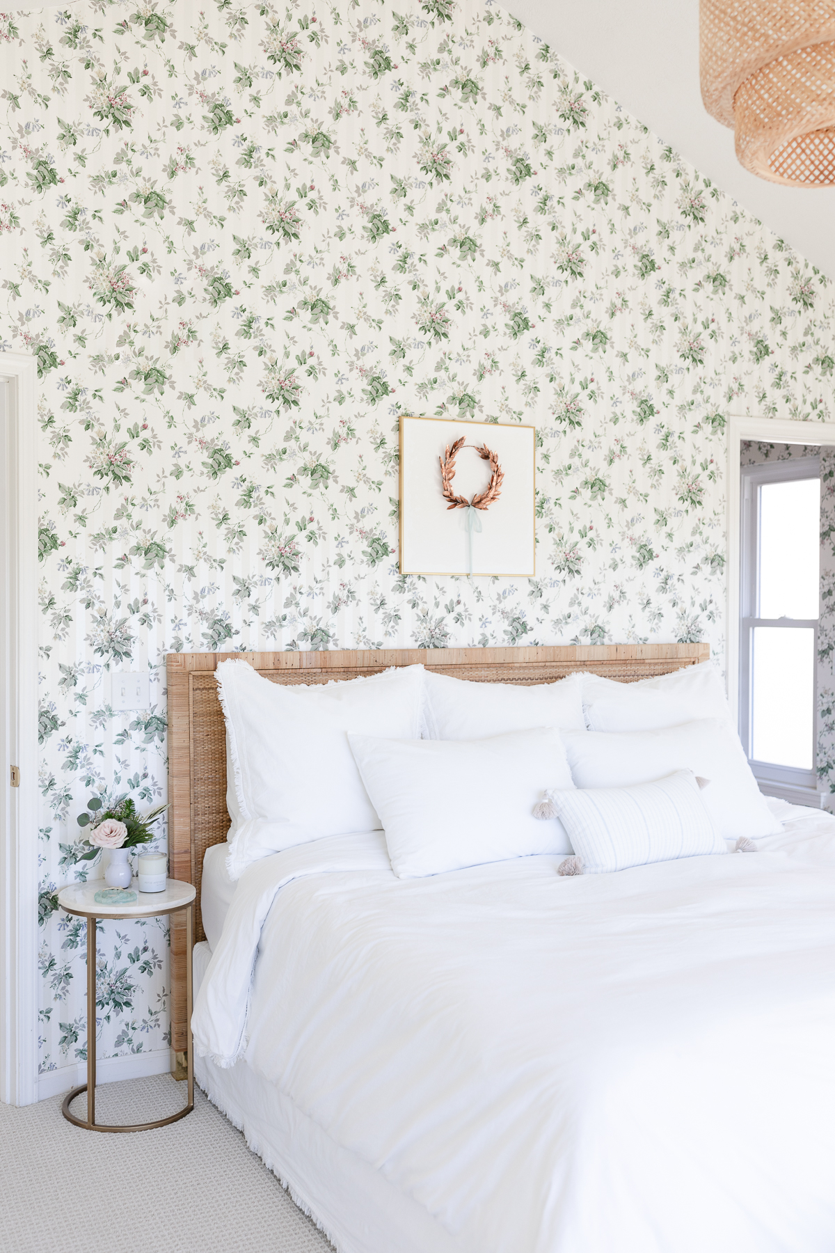 A white bedroom with dated green floral wallpaper.