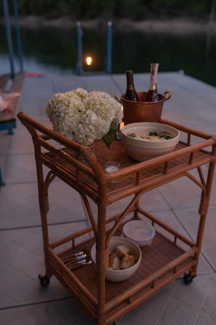 A small rattan bar cart set up for al fresco dining on a dock.