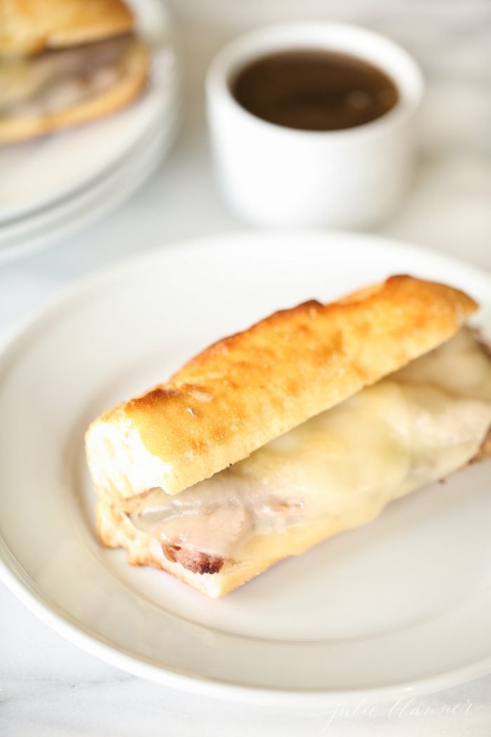 French dip sandwich with provolone cheese on white plate