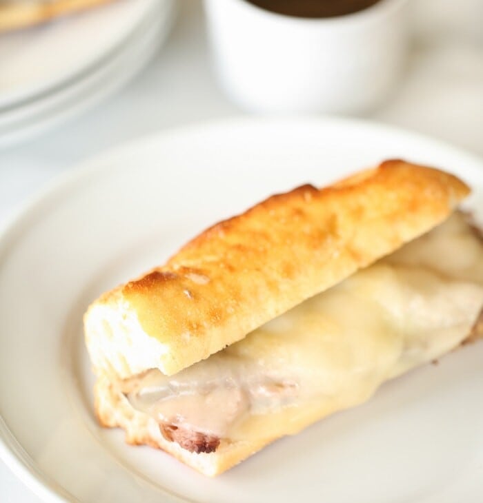 French dip sandwich with provolone cheese on white plate