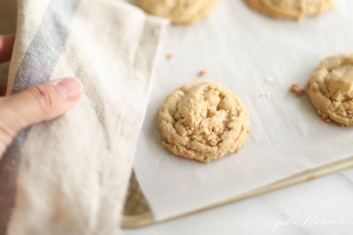 A hand holding a tray of freshly baked cookies