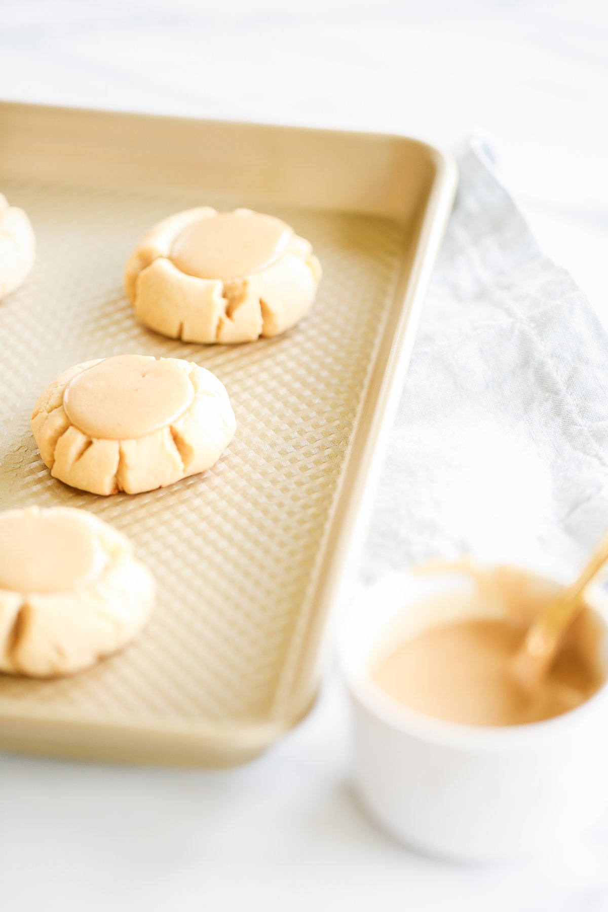 Peanut butter cookies with a caramel twist on a baking sheet.