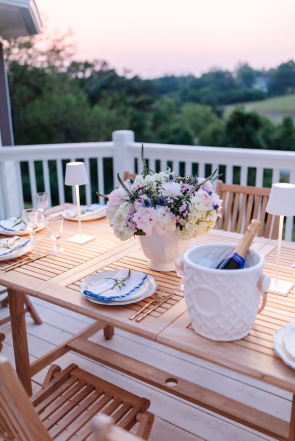 A patio furniture set for dinner on a deck at dusk.