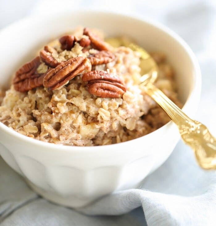 apple pie oatmeal in a white bowl with a gold spoon