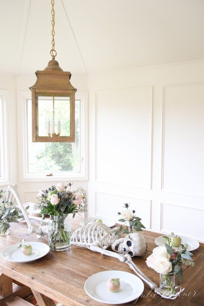 A skeleton on a dining table with fresh flowers