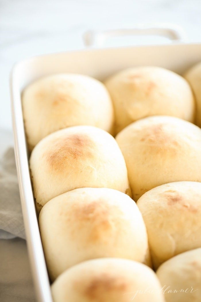 A white baking dish filled with homemade dinner rolls.