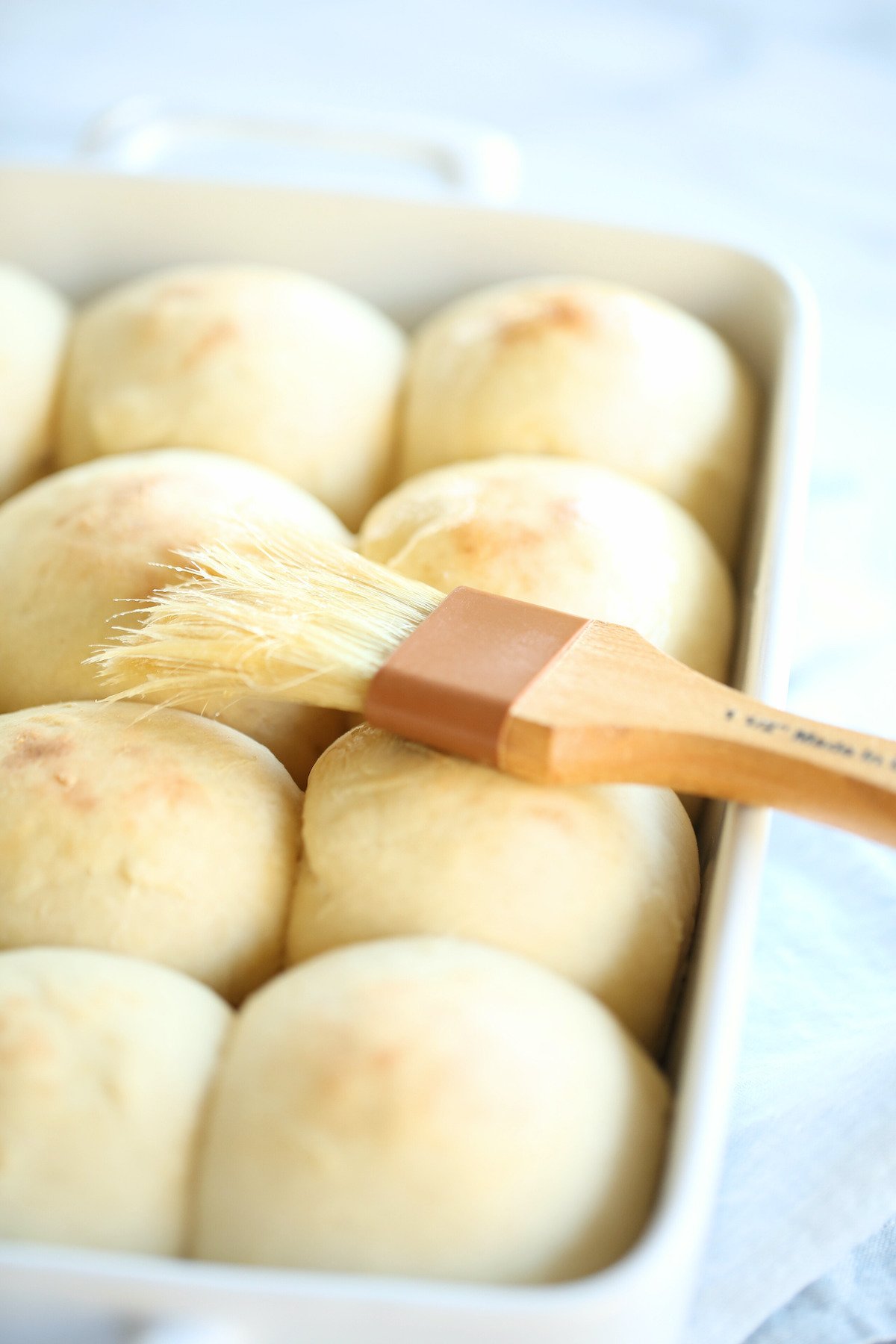 A white baking pan full of homemade dinner rolls.