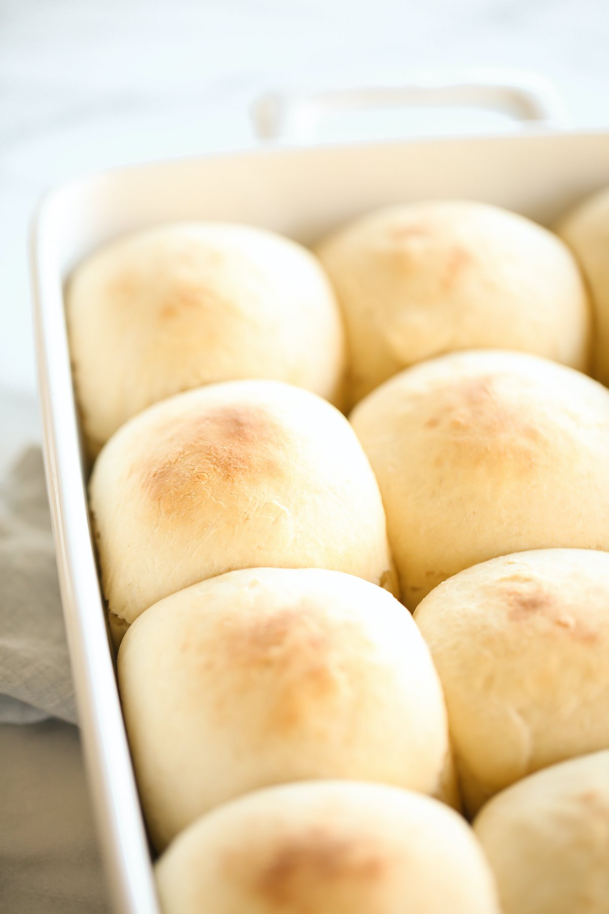 A white baking pan full of homemade dinner rolls.