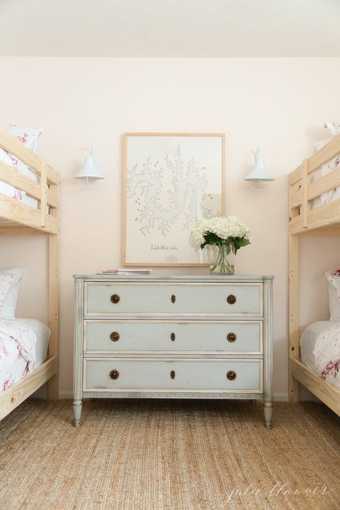 A soft pink bedroom with wooden bunk beds and feminine pink floral bedding.