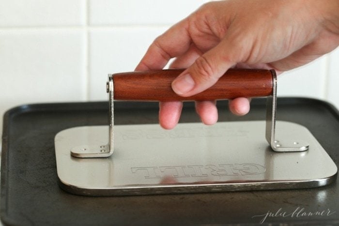 A hand on a grill press making a stroopwafel without a pizelle 