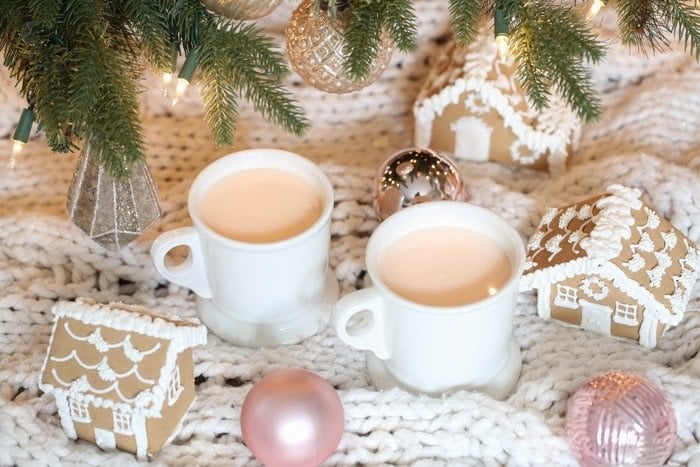 Two mugs of pink hot chocolate under christmas tree