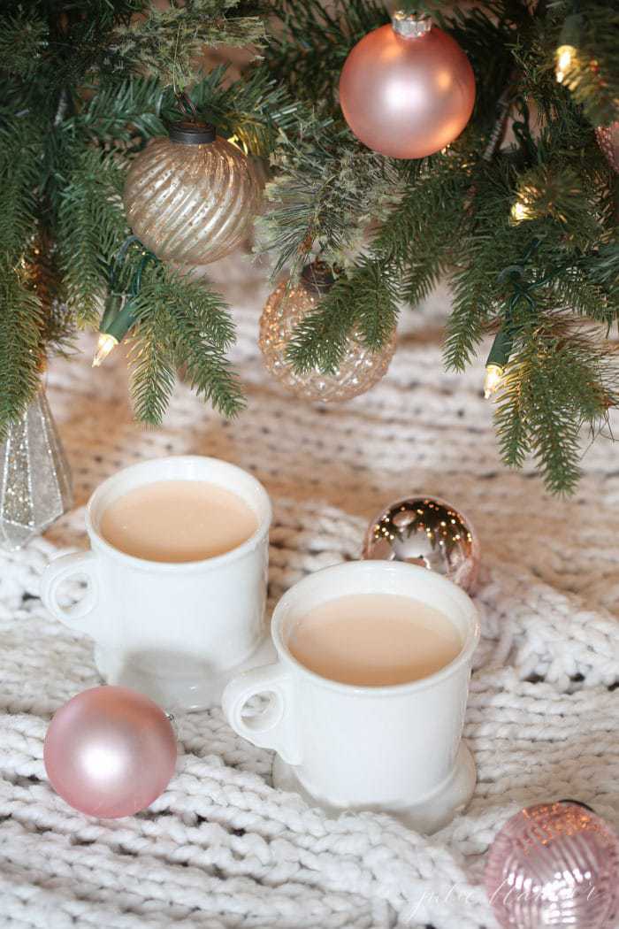 Pink hot chocolate in a white mug under a christmas tree.