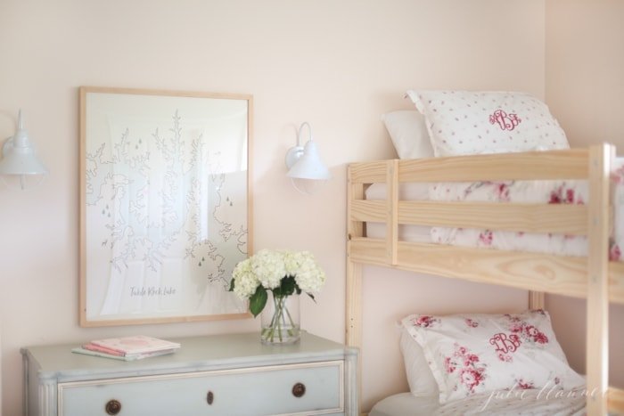 A soft pink bedroom with solid wood bunk beds and feminine pink floral bedding.