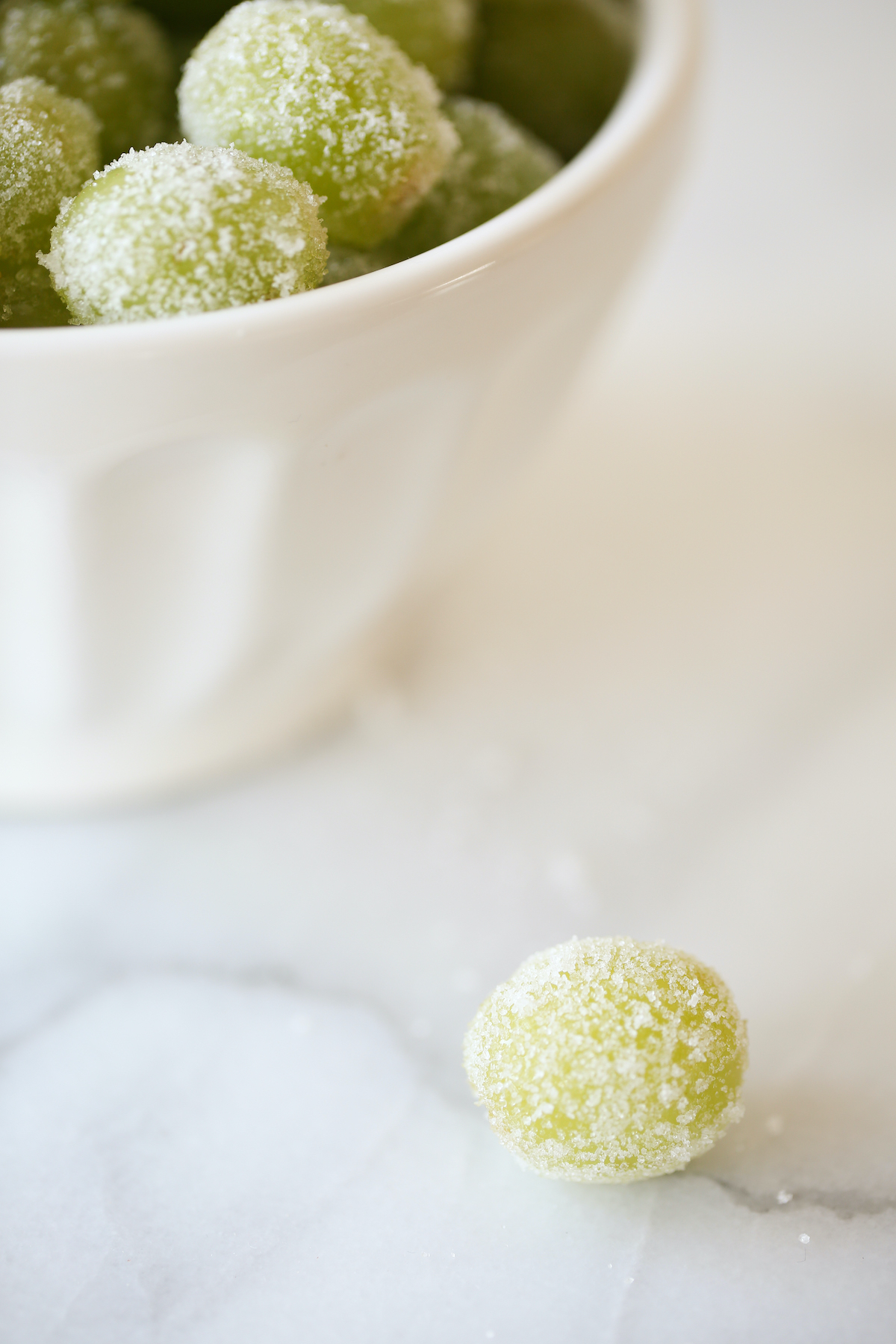 A white bowl of green sugared champagne grapes.