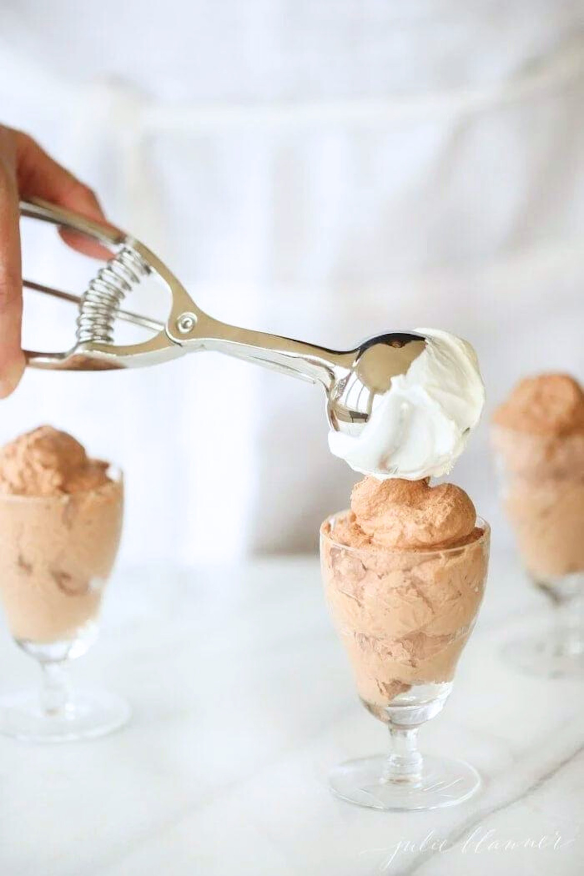 A person expertly scooping chocolate ice cream into small cups, making it the perfect easy chocolate mousse recipe.