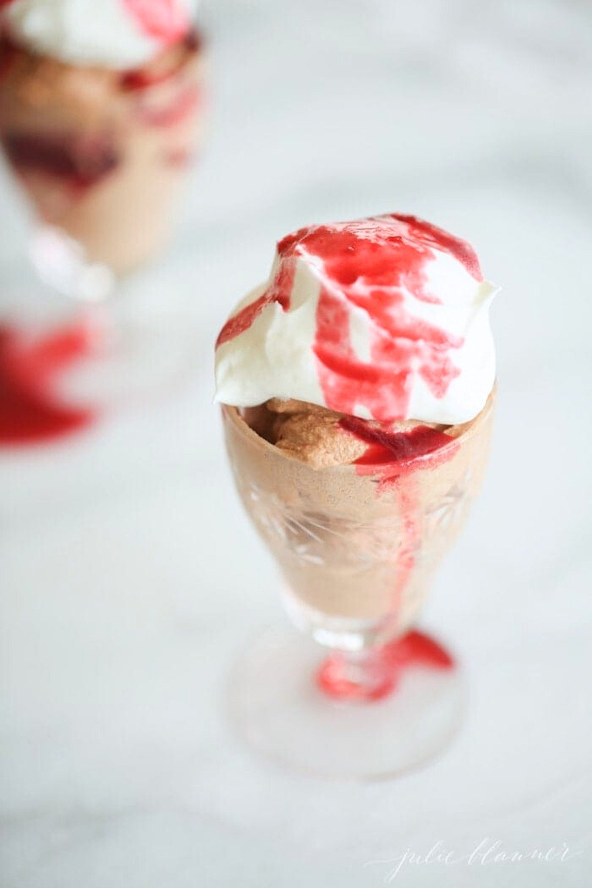An easy chocolate mousse recipe topped with whipped cream and raspberry sauce.