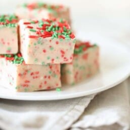 A stack of white chocolate fudge with Christmas sprinkles on a white plate.