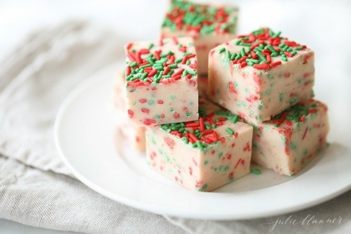 white fudge slices with christmas sprinkles on a white plate.