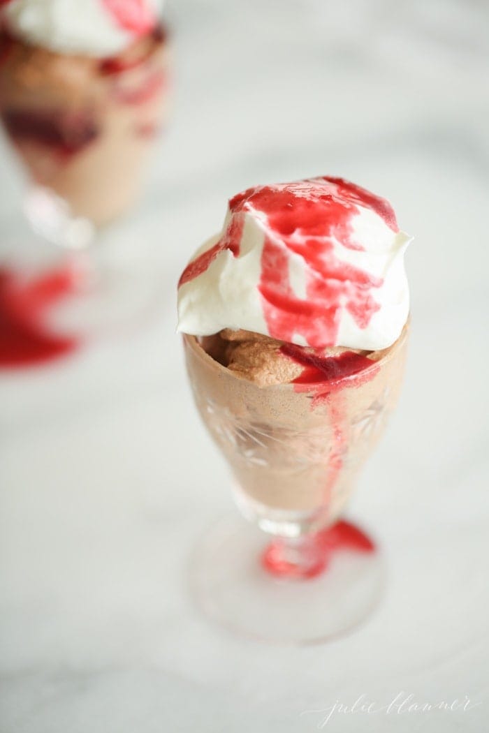 chocolate mousse in glass with a red sauce and cream