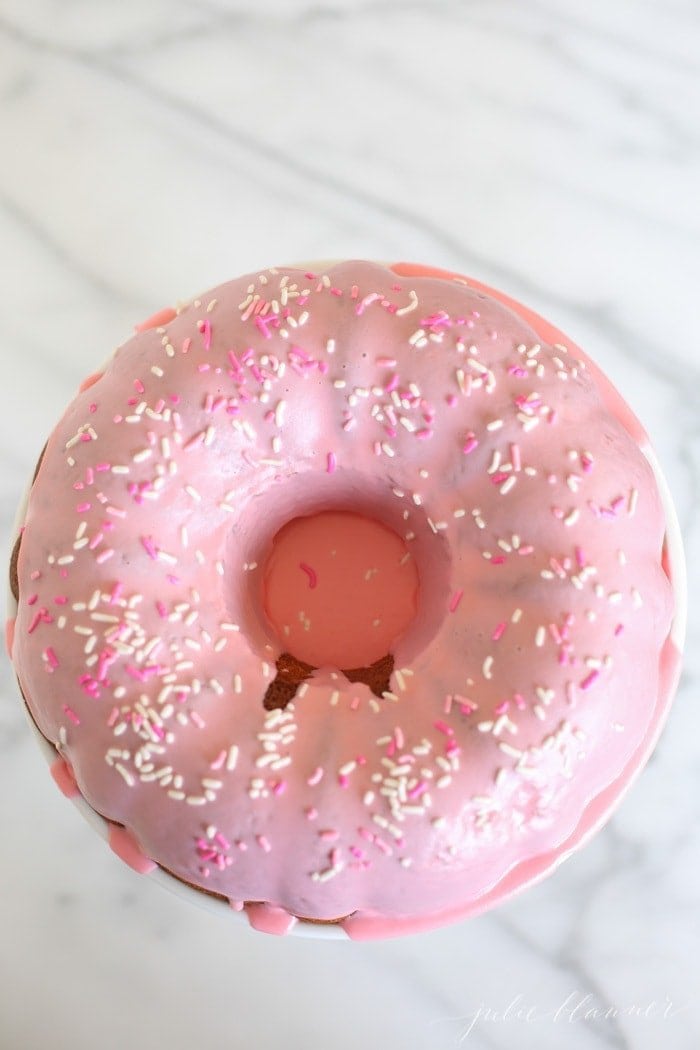 overhead of pink glazed donut cake with sprinkles