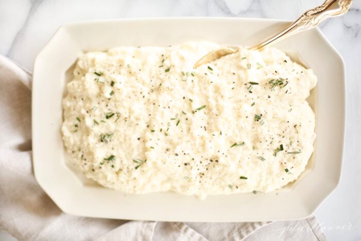 A white plate with mashed cauliflower on it.