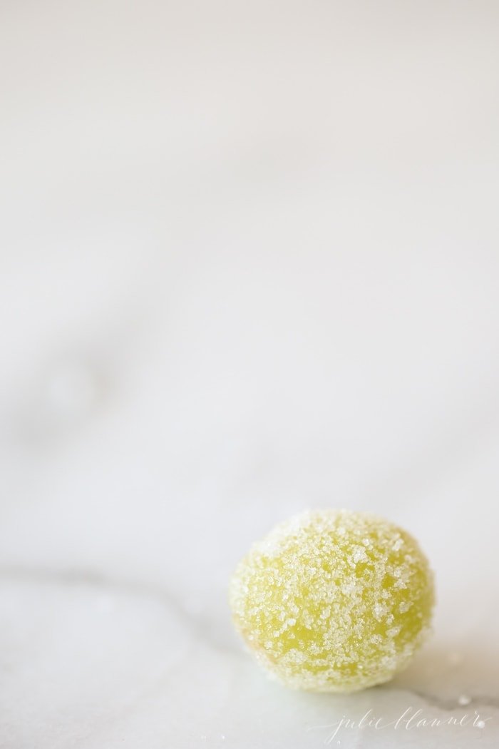 Sugared champagne grape on a white surface.