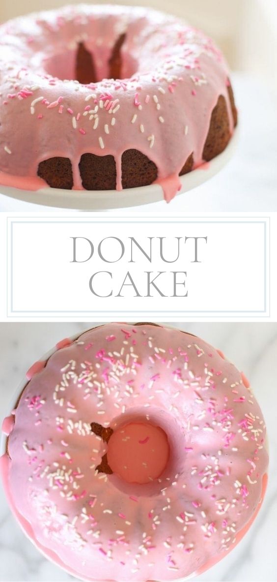 On a white cake stand there is a donut cake with pink icing and pink and white sprinkles.