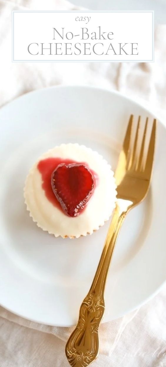 On a round white plate, there is a single no-bake cheesecake topped with a sliced fresh strawberry next to a golden fork.