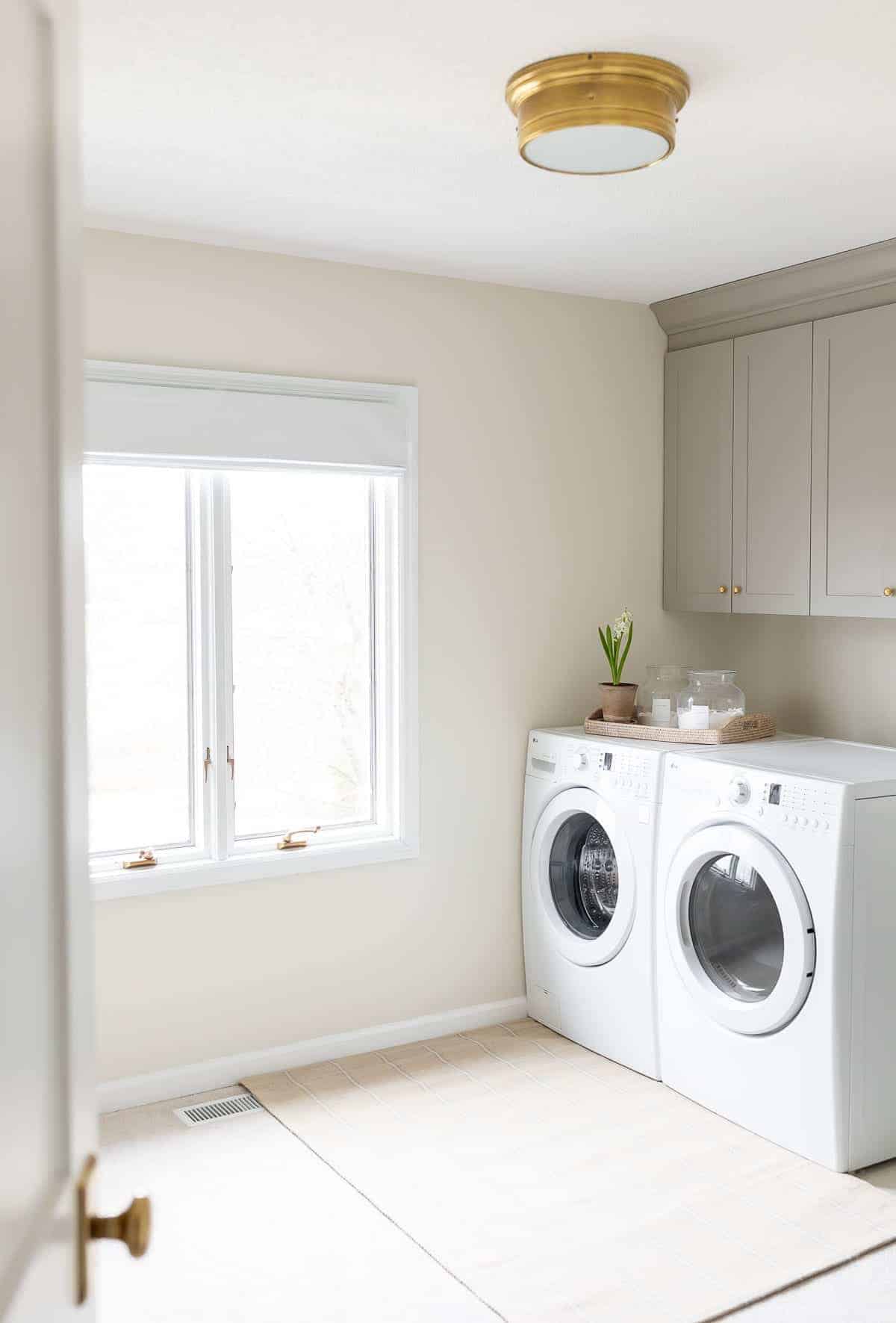 A laundry room with gray full overlay cabinets above the washer and dryer.