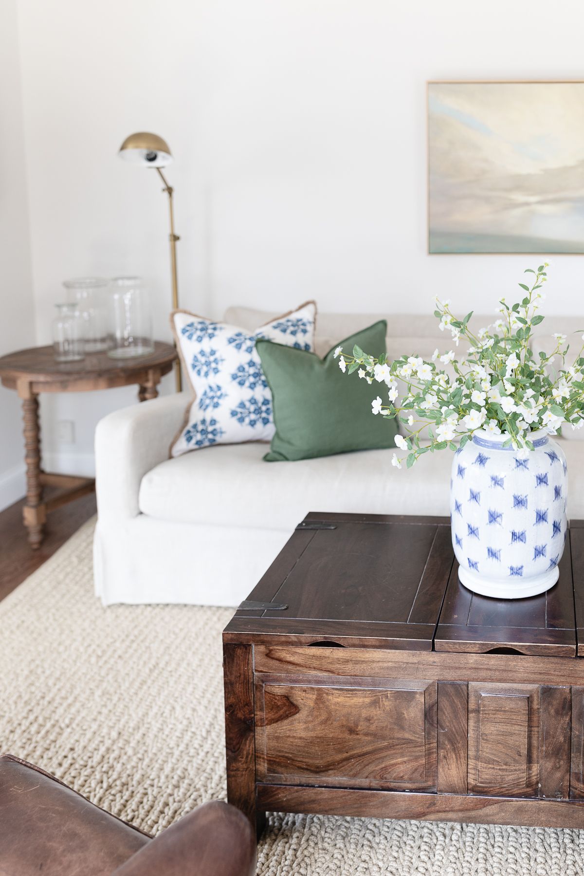 A white living room with a cream linen sofa and wood coffee table.