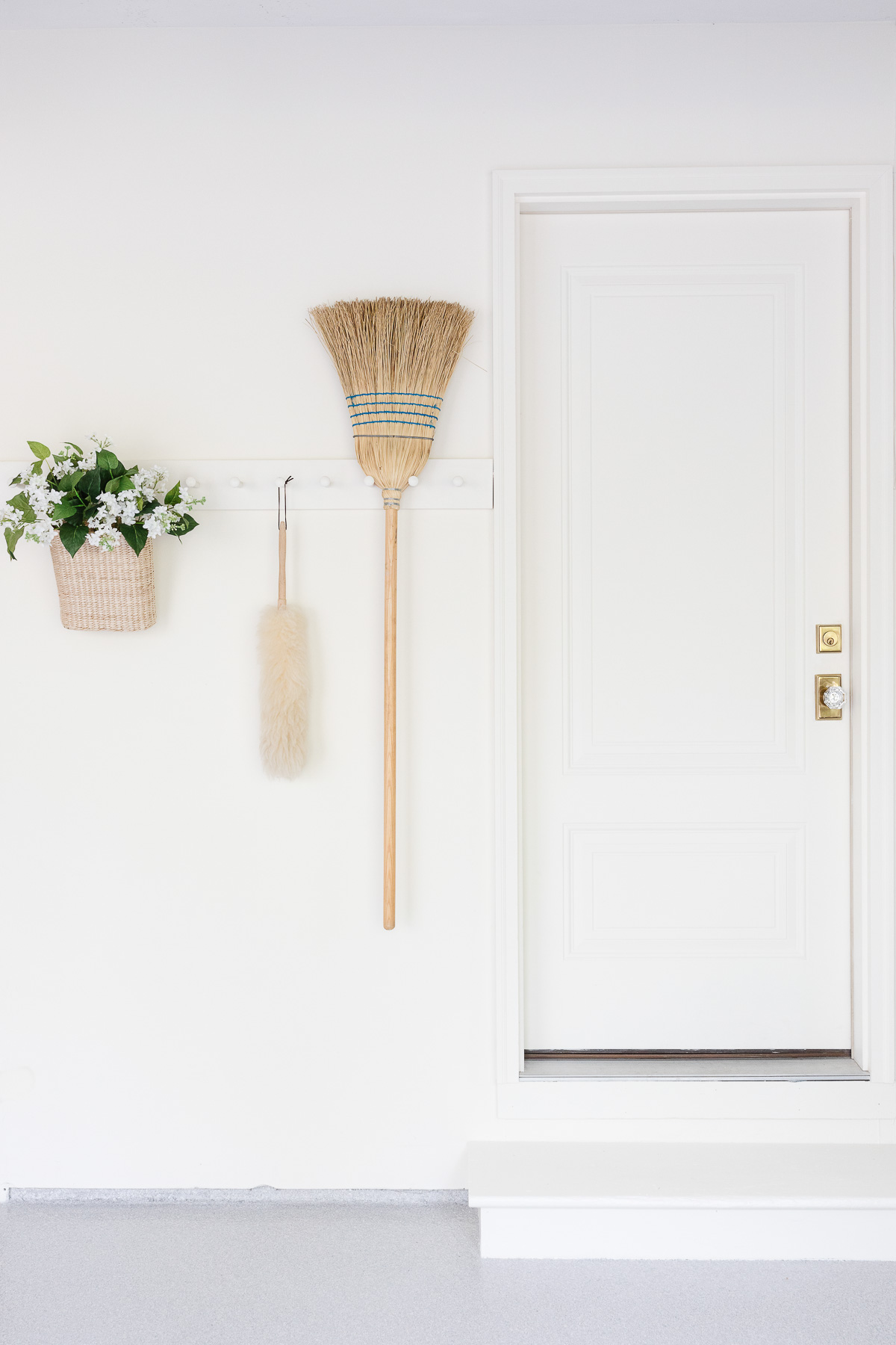 A white wall with peg rail holding clean supplies in a garage organization guide.