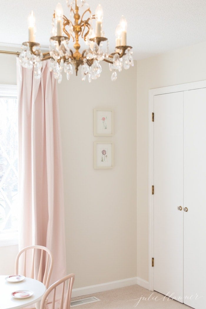 A girl's bedroom with pink blackout curtains and a gold chandelier.