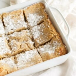 A white baking dish full of sliced gooey butter cake without a cake mix.