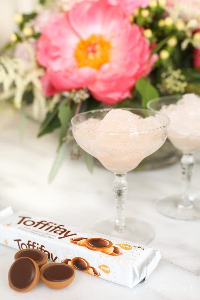 Frose in a cocktail glass next to flowers and chocolate