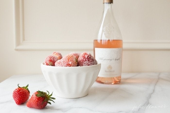 Sugar coated drunken strawberries next to a bottle of rose wine