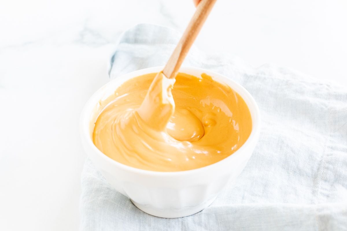 A white bowl with melted peanut butter inside.