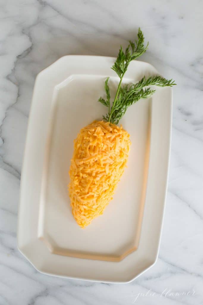 A carrot cheese ball on a white platter
