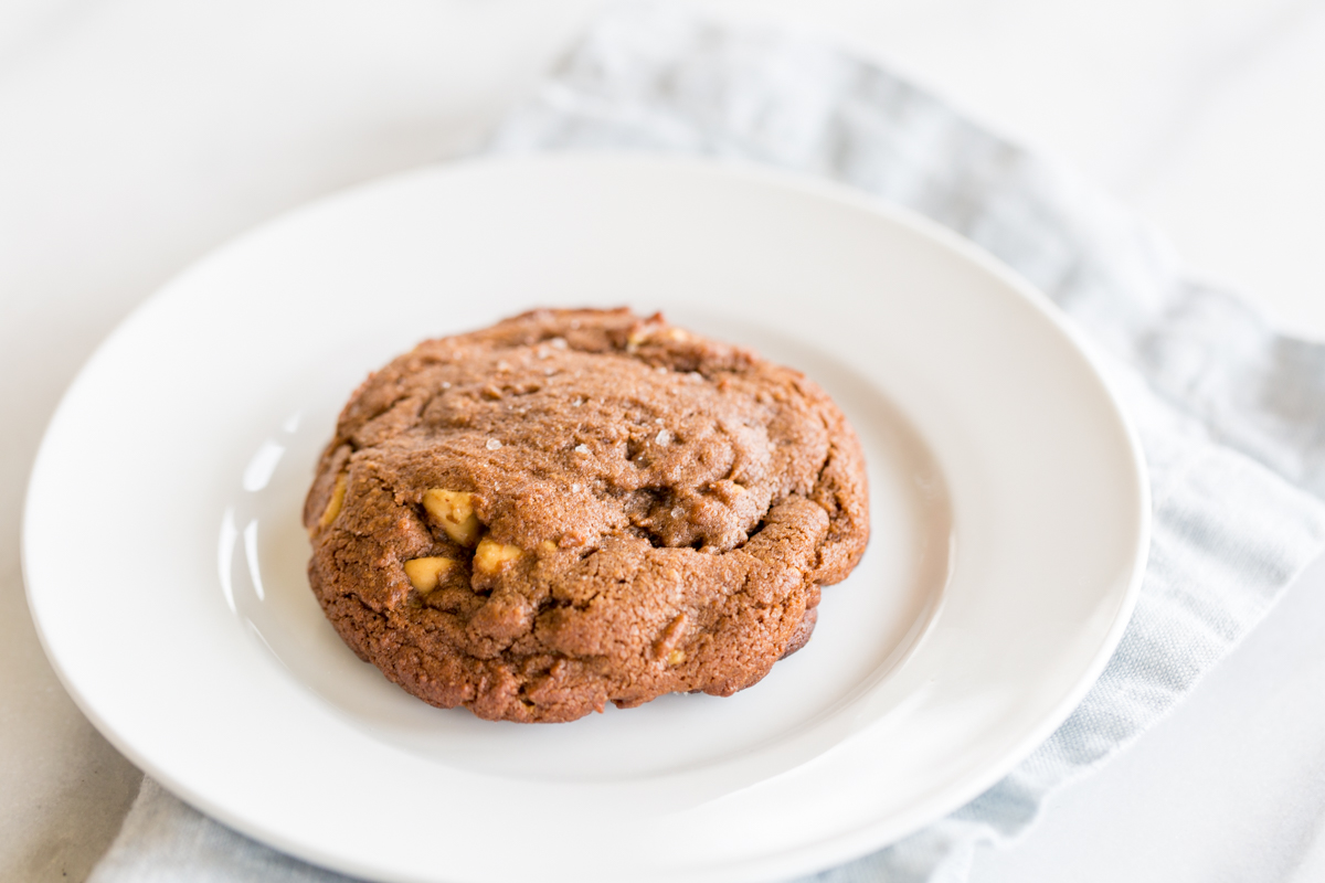 A chocolate cookie with peanut butter chips on a white plate.