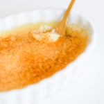 Easy creme brulee served in a white dish with a gold spoon.