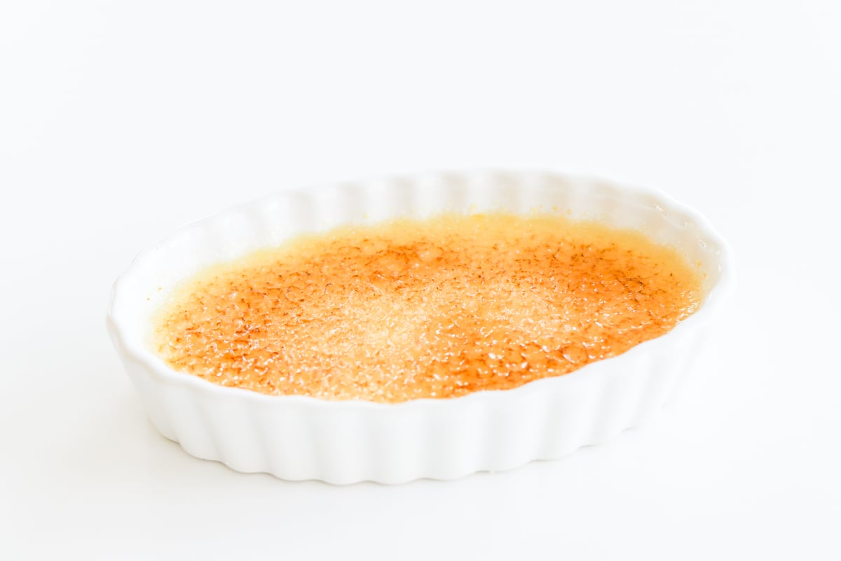 An easy creme brulee in a white dish on a white background.