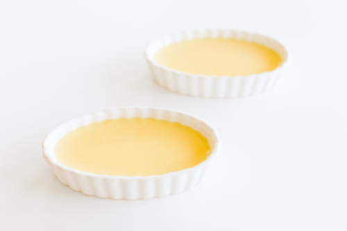 Two bowls of easy creme brulee on a white surface.
