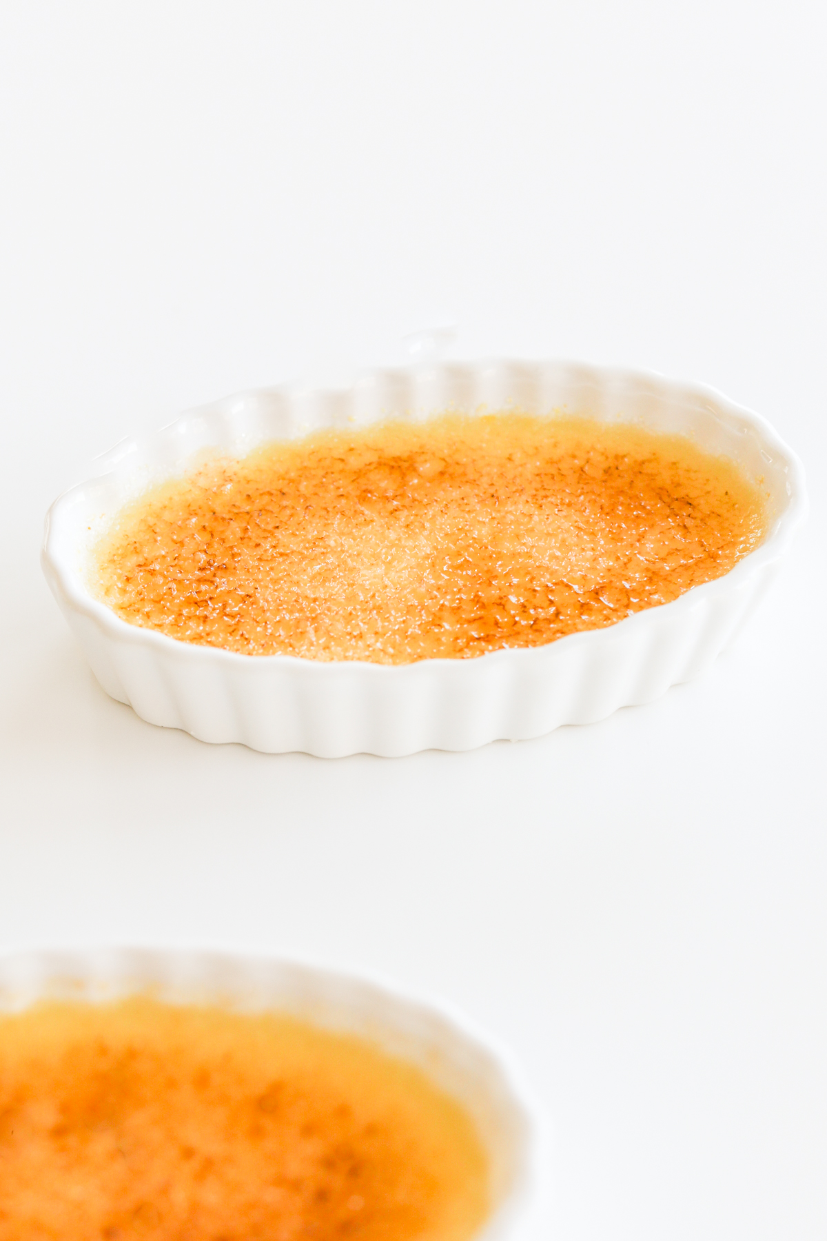 Two dishes of easy creme brulee on a white surface.